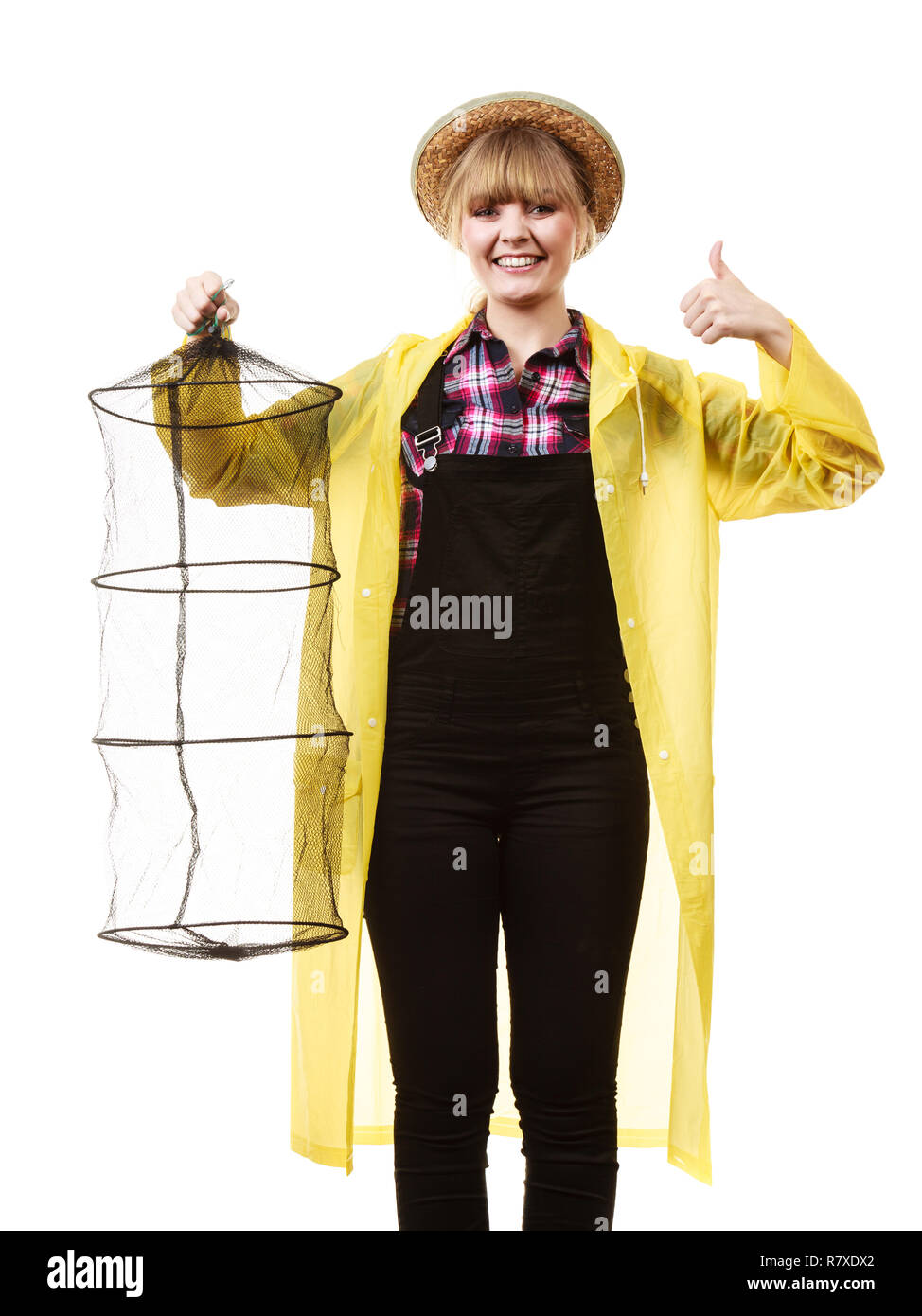 Spinning, angling, cheerful fisherwoman concept. Happy woman in yellow raincoat holding empty fishing keepnet, having fun. Stock Photo