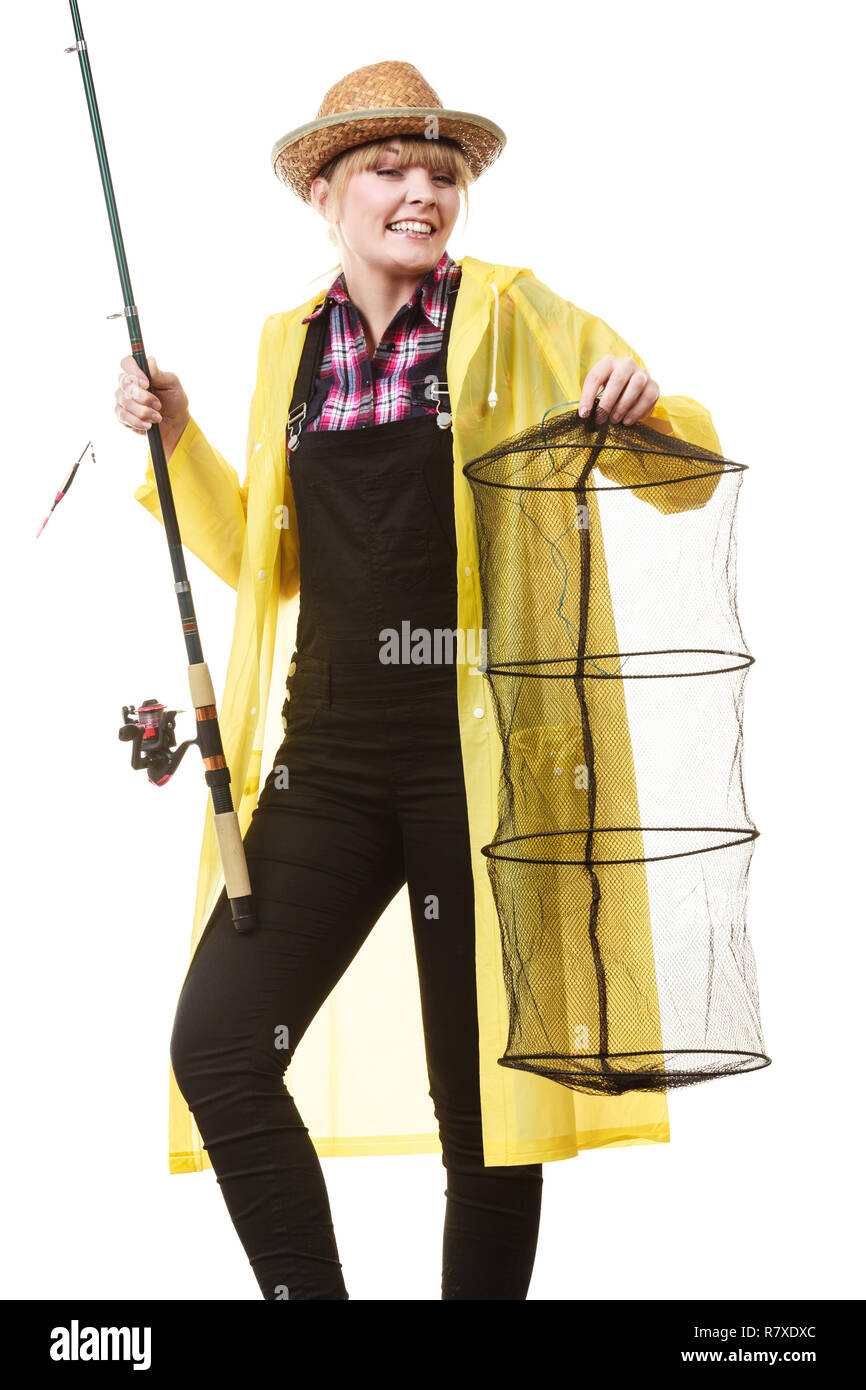 Spinning, angling, cheerful fisherwoman concept. Happy woman in yellow raincoat holding fishing rod and keepnet having fun. Stock Photo