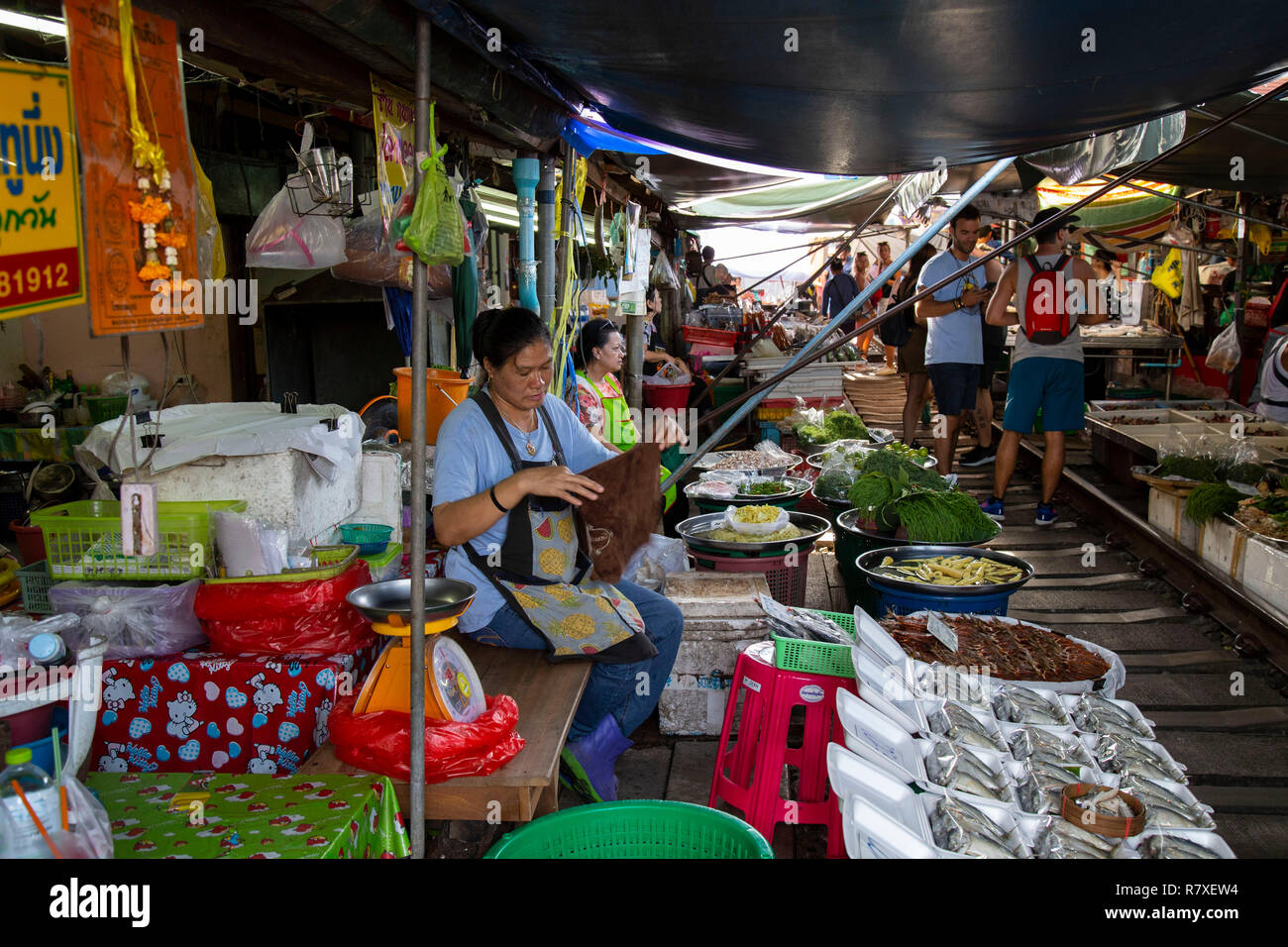 Tourists strolling between the tracks of the train market and buying at the stops on the sides of the vai before the train returns and the shops have Stock Photo