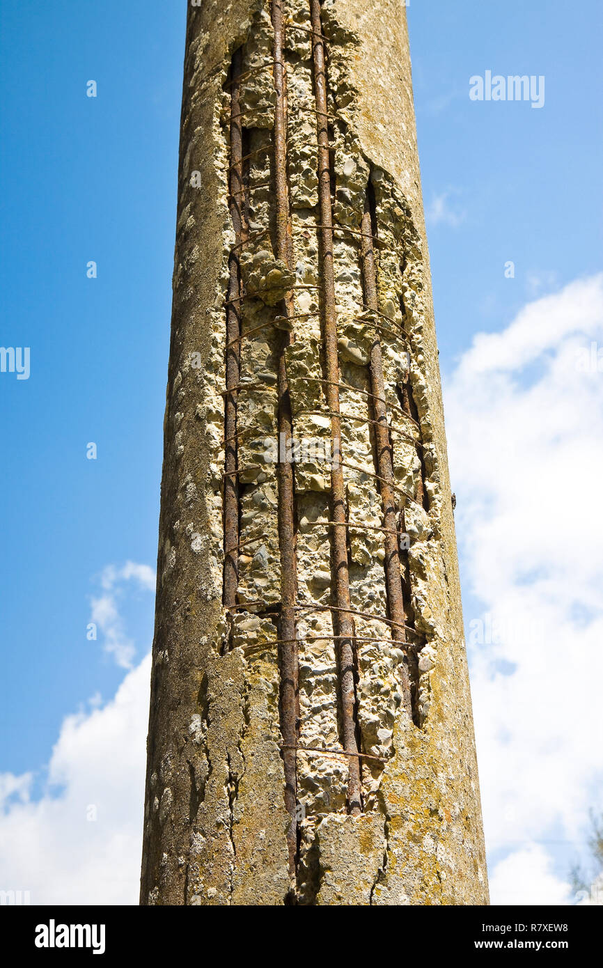 Danger cracked concrete electricity pylon with reinforcing iron bars in