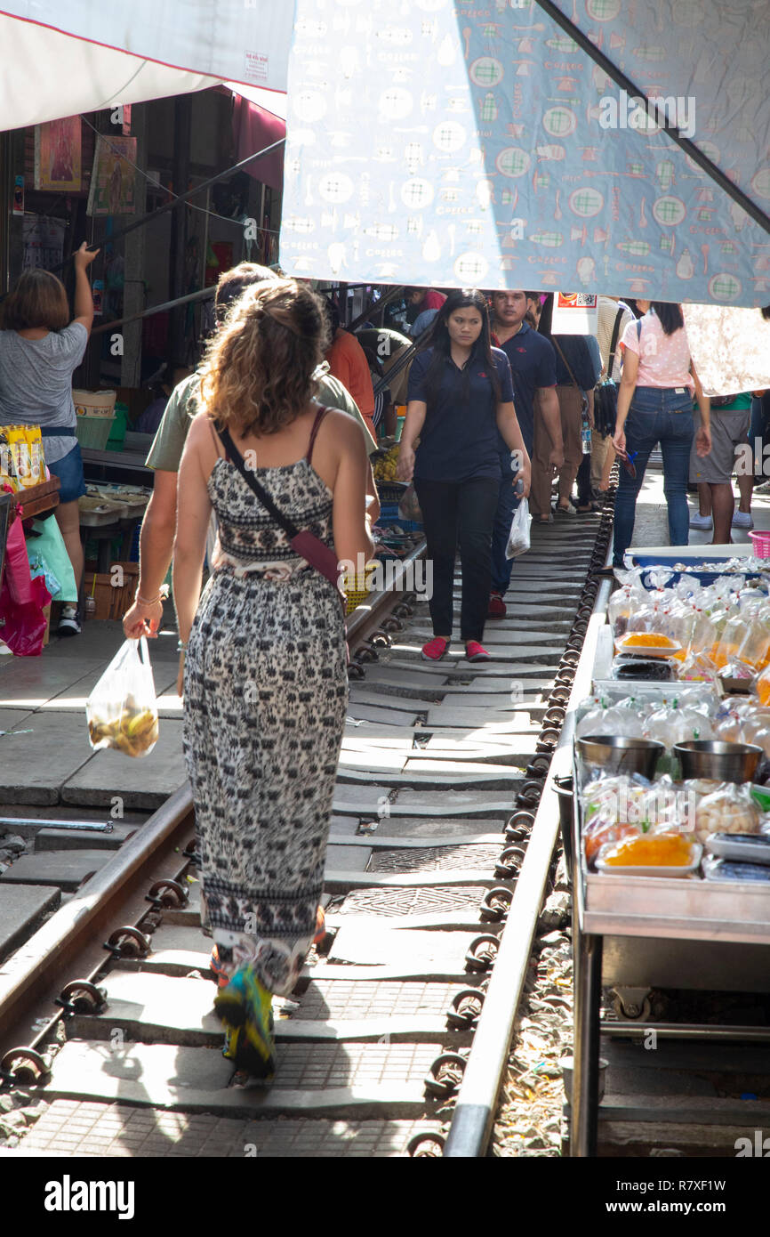 Tourists strolling between the tracks of the train market and buying at the stops on the sides of the vai before the train returns and the shops have Stock Photo