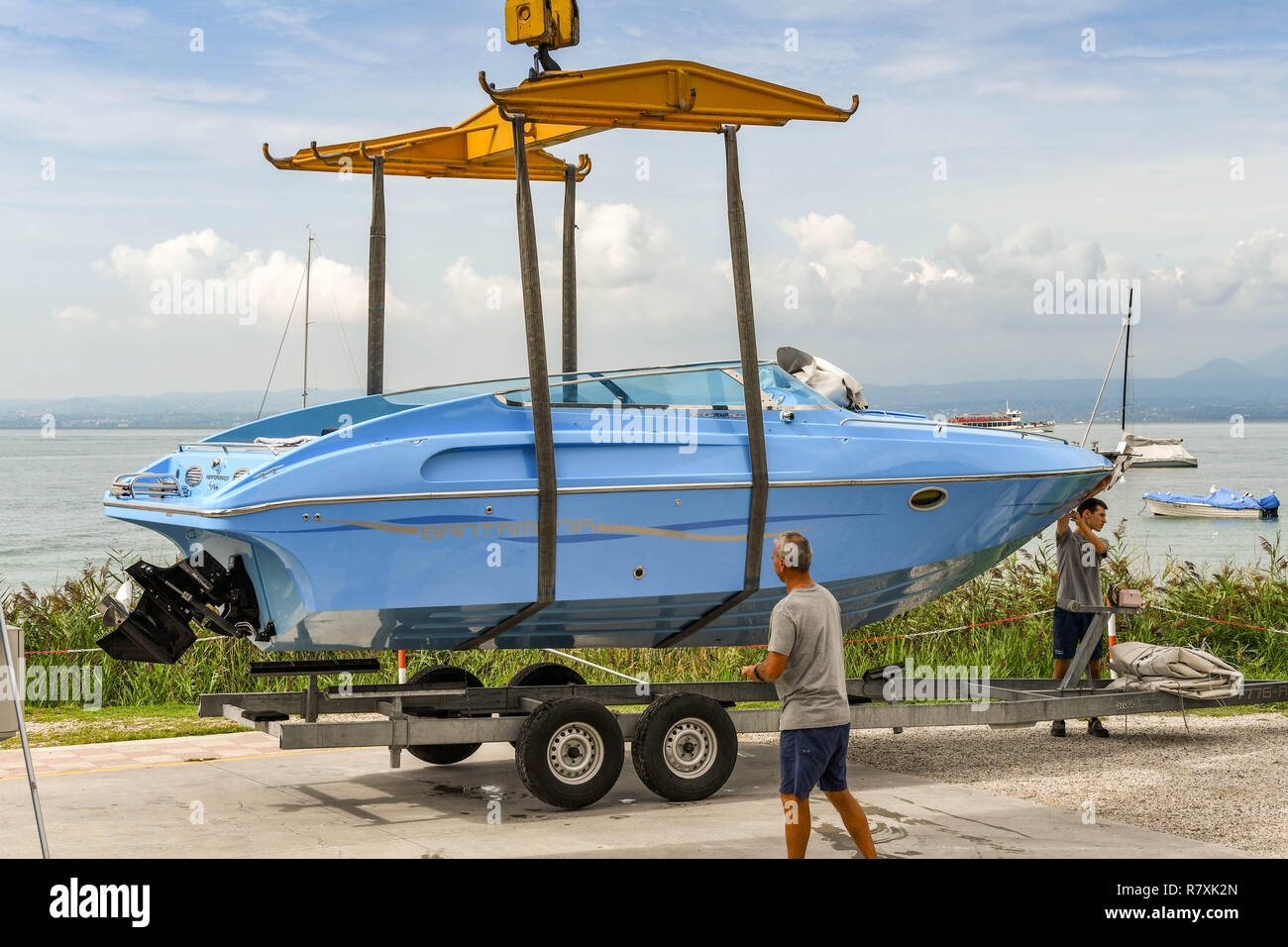 BARDOLINO, LAKE GARDA, ITALY - SEPTEMBER 2018: Crane lifting a boat off a trailer to move it into the water at a marina on Lake Garda near Bardolino. Stock Photo