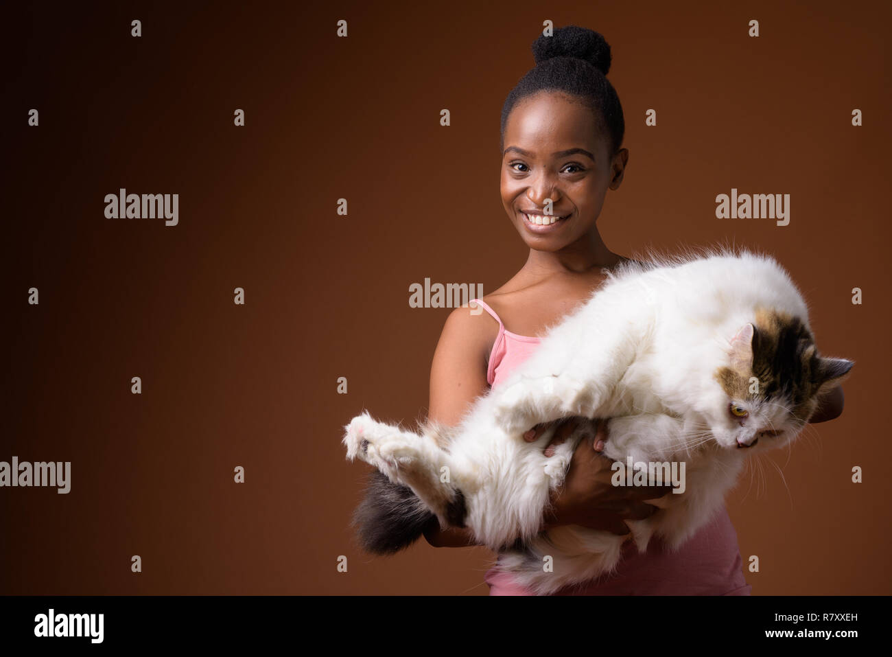 Young beautiful African Zulu woman holding cat while smiling Stock Photo