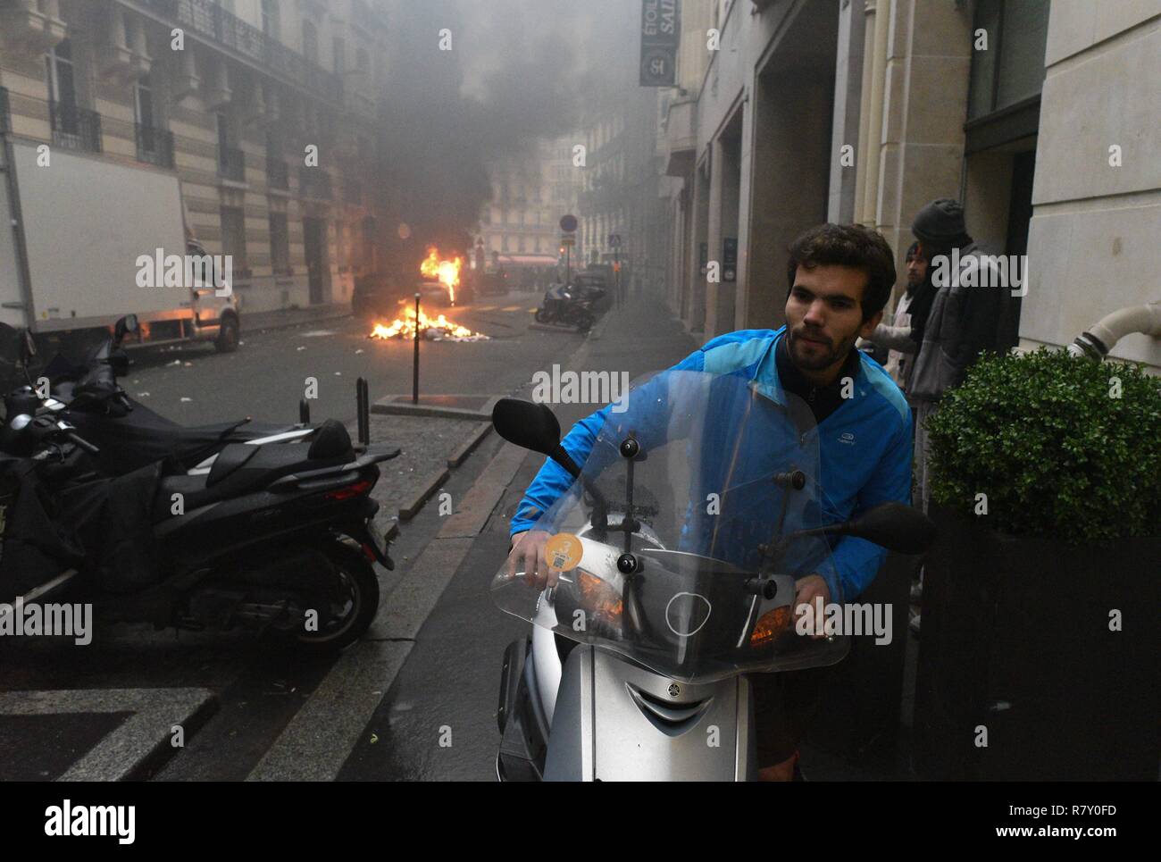 December 01, 2018 - Paris, France: Jimmy Crombez, a 32 year-old owner of a start-up, tries to take away his scooter away from the street where he lives, where several vehicles have been put on fire.  Un habitant recupere son scooter pour l'eloigner tandis que des gilets jaunes et des casseurs mettent le tau a des vehicules dans sa rue en marge d e l'acte 3 des gilets jaunes a Paris. Cette manifestation a rapidement degenere en affrontement avec les CRS filtrant l'entree de l'avenue des Champs-Elysees.  *** FRANCE OUT / NO SALES TO FRENCH MEDIA *** Stock Photo