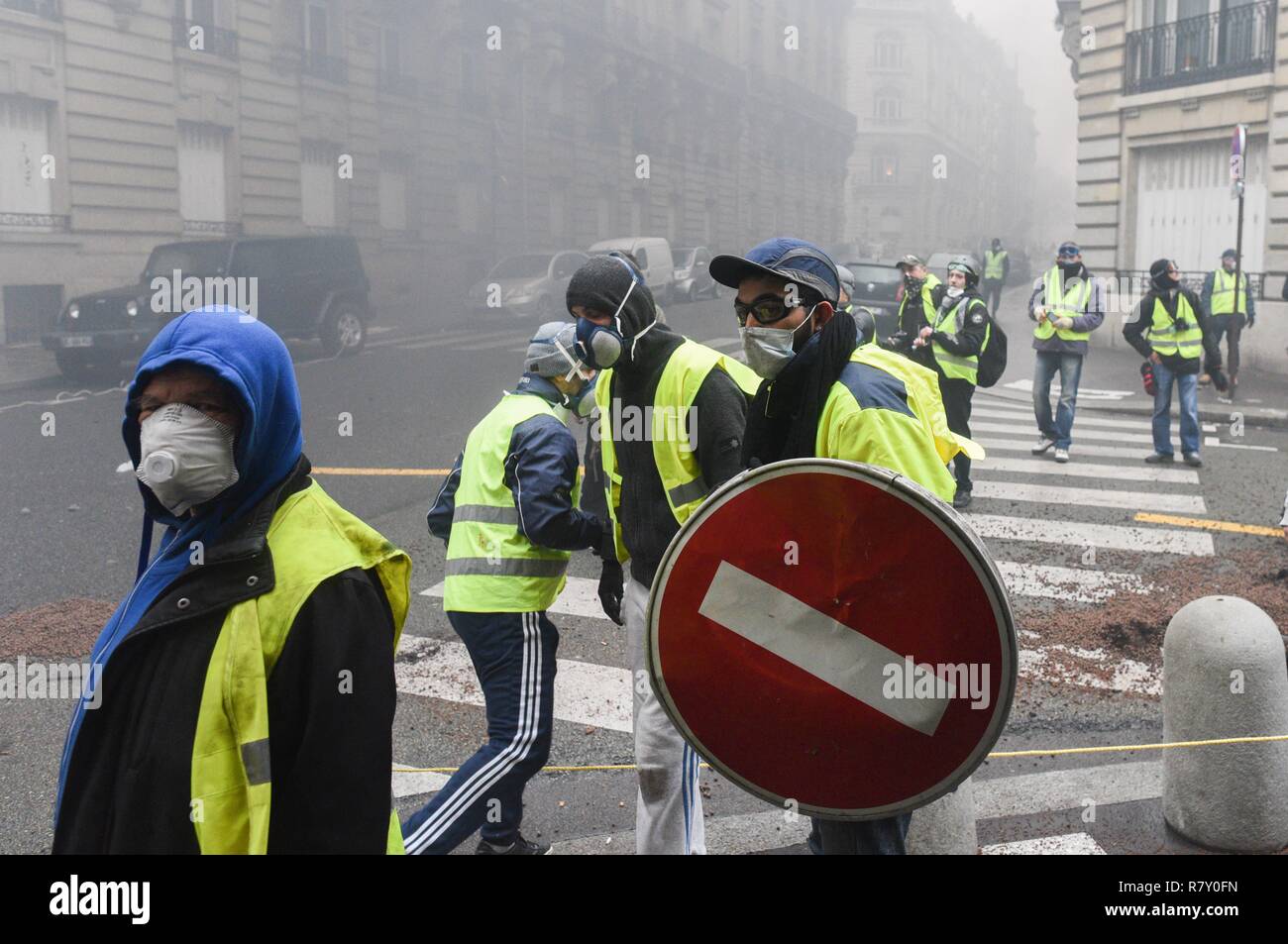 December 01, 2018 - Paris, France: A Yellow vest protester uses a road sign  as a shield in a side street near the Champs-Elysees avenue, where several  vehicles were burnt. Protesters clashed
