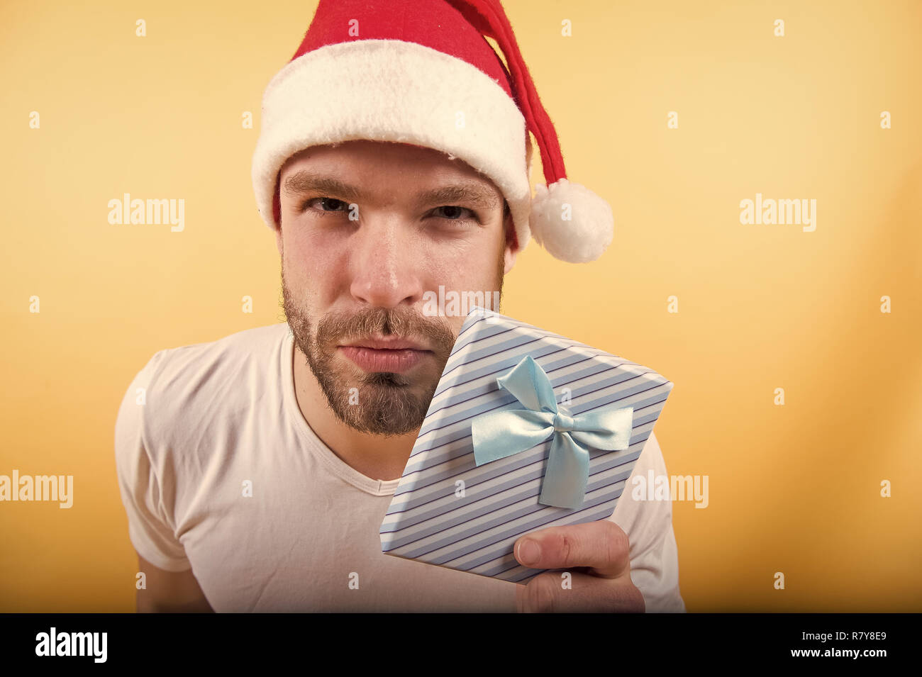 Christmas Ribbon Man Macho hold xmas box with blue ribbon. Man in santa hat with present on ...