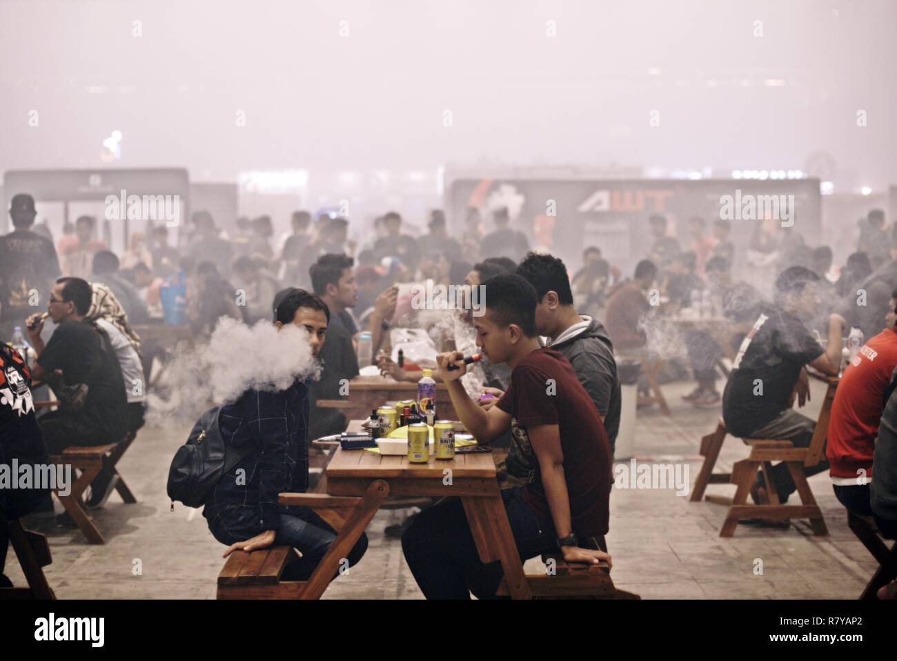 Visitors puff on their e-cigarettes after having meals during the 2018 Vape Fair at Jakarta International Expo, Jakarta, Indonesia. Stock Photo