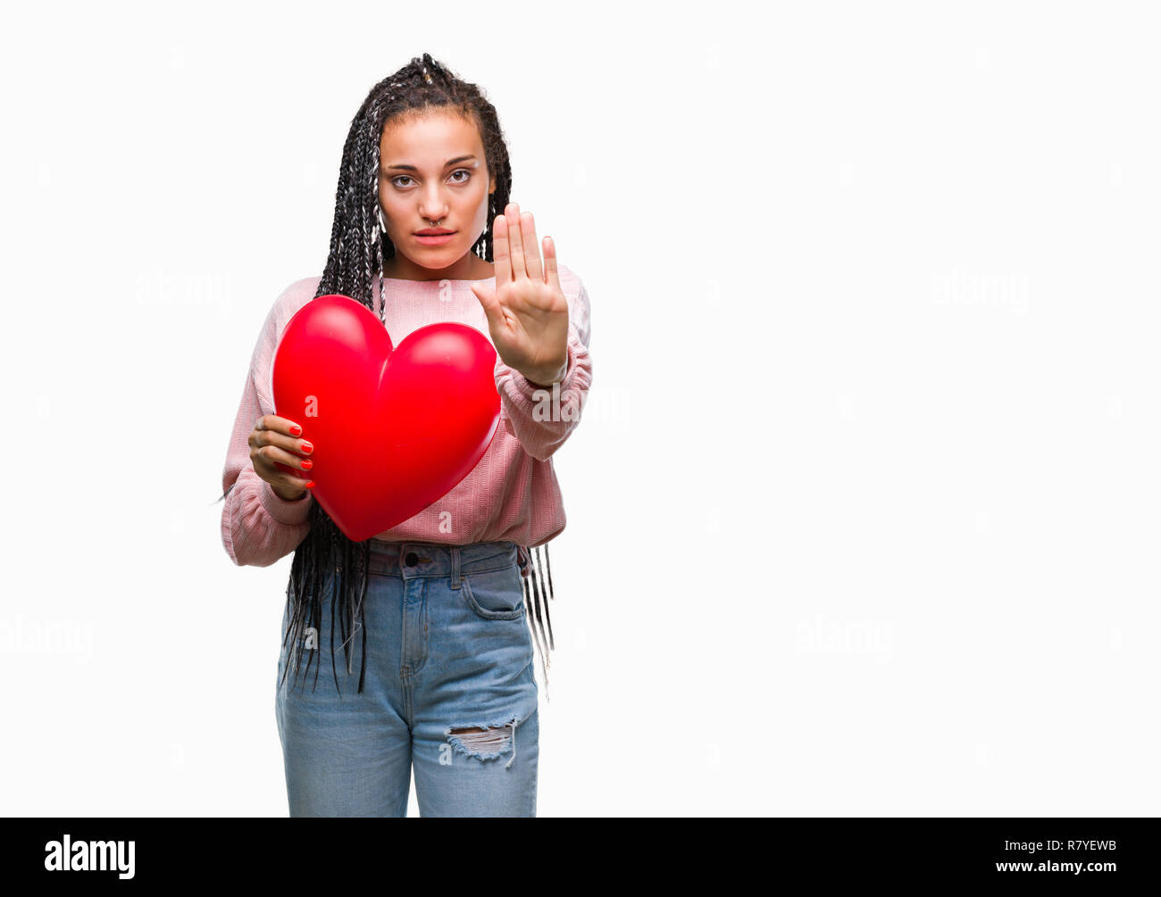 Young braided hair african american girl holding read heart over isolated background with open hand doing stop sign with serious and confident express Stock Photo