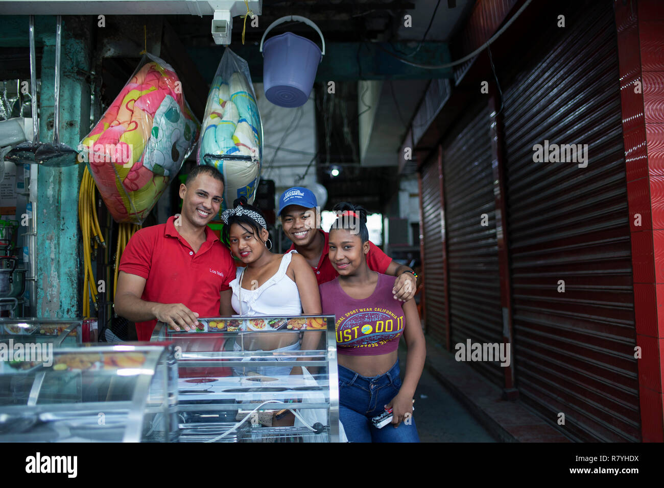 Group photo of smiling, young Colombian people at Bazurto market (Mercado Bazurto) outside a homeware shop. Cartagena de Indias, Colombia. Oct 2018 Stock Photo