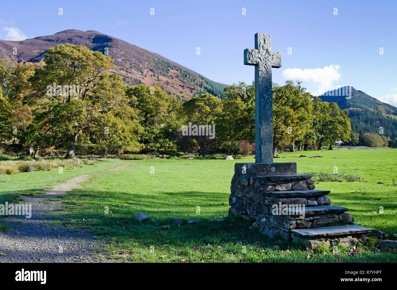 Old stone cross mounted on rustic stone steps in field by St Bega's Church, Bassenthwaite, Ullock Pike and Dodd rising behind, Lake District, Cumbria Stock Photo