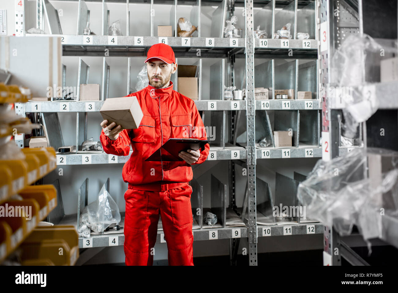 Warehouse worker in red uniform filling some documents checking goods