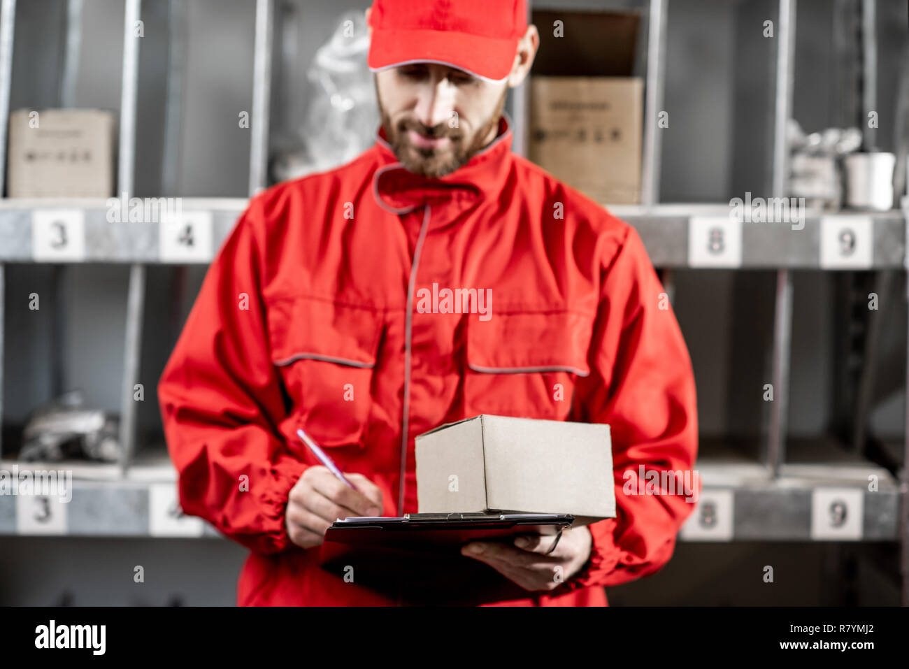 Warehouse worker in red uniform filling some documents checking goods