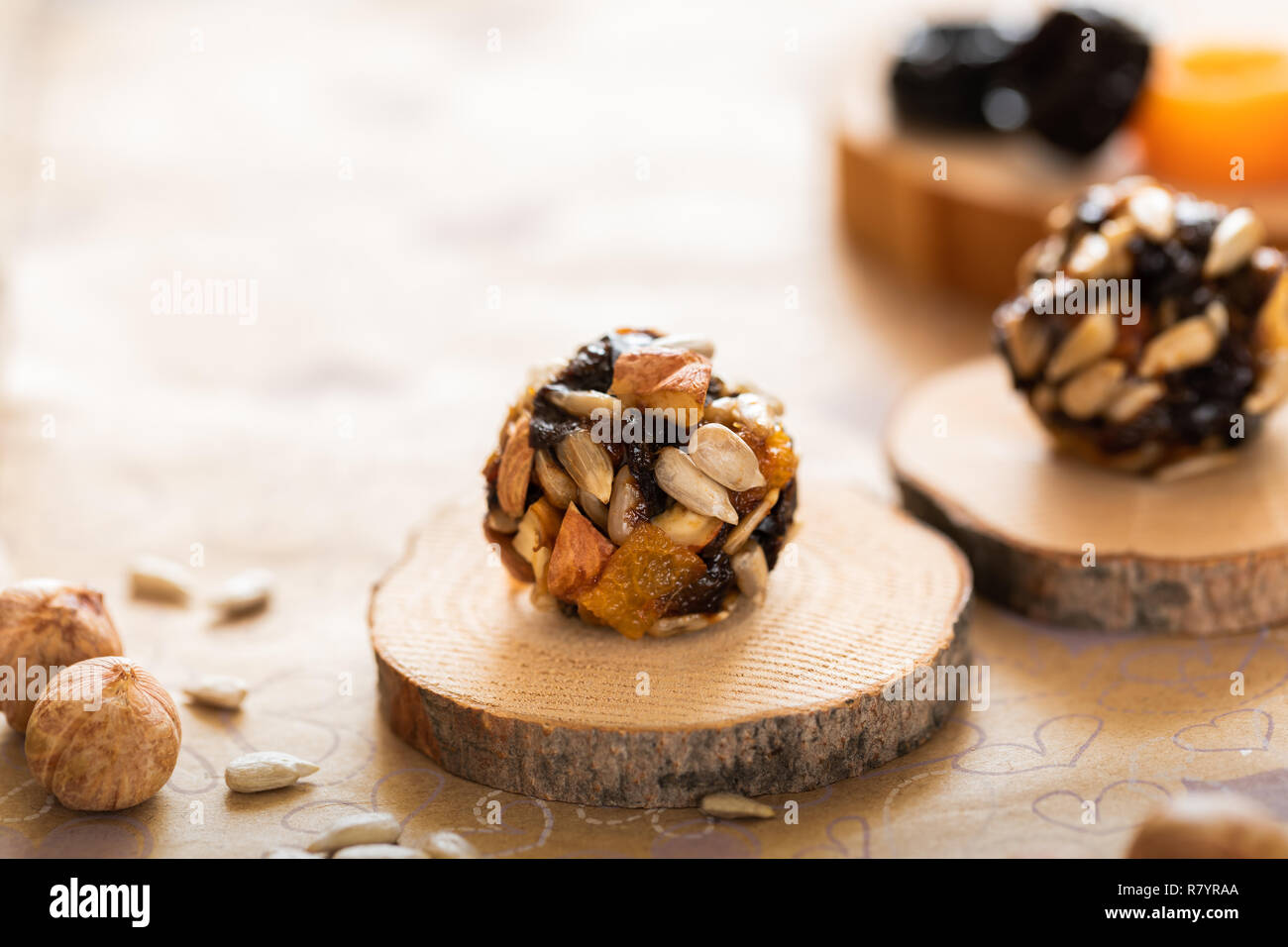 Handmade energy balls on wooden saw cuts and ingredients for their preparation on paper background. Stock Photo