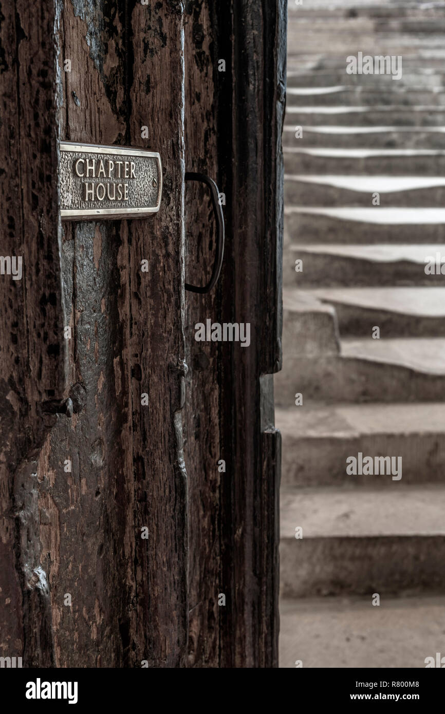 A small sign on the ancient wooden door shows the way to the historic Chapter House steps at Wells Cathedral in Somerset. Stock Photo