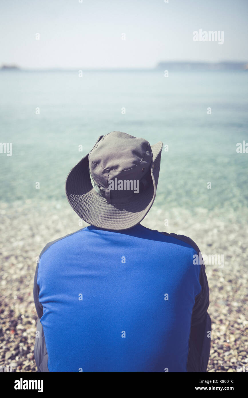 Tourist wearing a hat standing on a beach and looking at the stunning Croatian coast in Dubrovnik Stock Photo