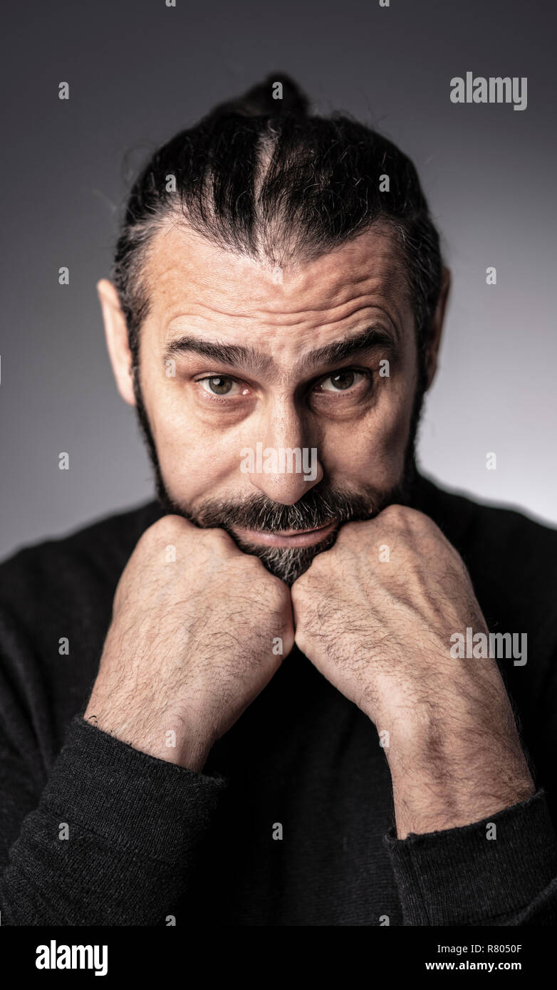 portrait of man with long hair studio shot thinking position Stock Photo