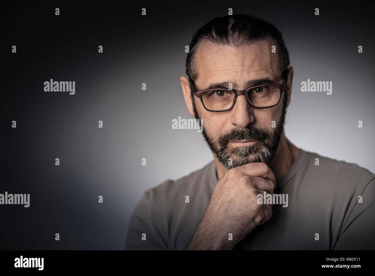 portrait of man with long hair and glasses studio shot thinking position Stock Photo