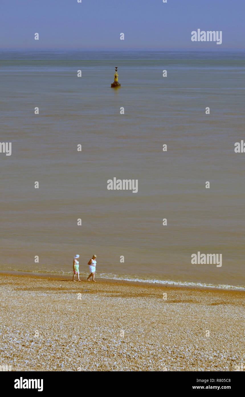 two middle aged women walking on beach at Dungeness Kent England wearing bras Stock Photo