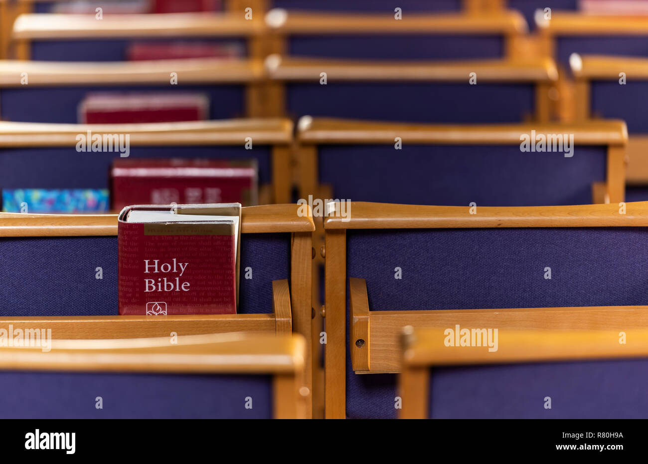 Brockenhurst, England - October 23, 2018: Red holy bible on a blue chair in the church of Brockenhurst. Stock Photo