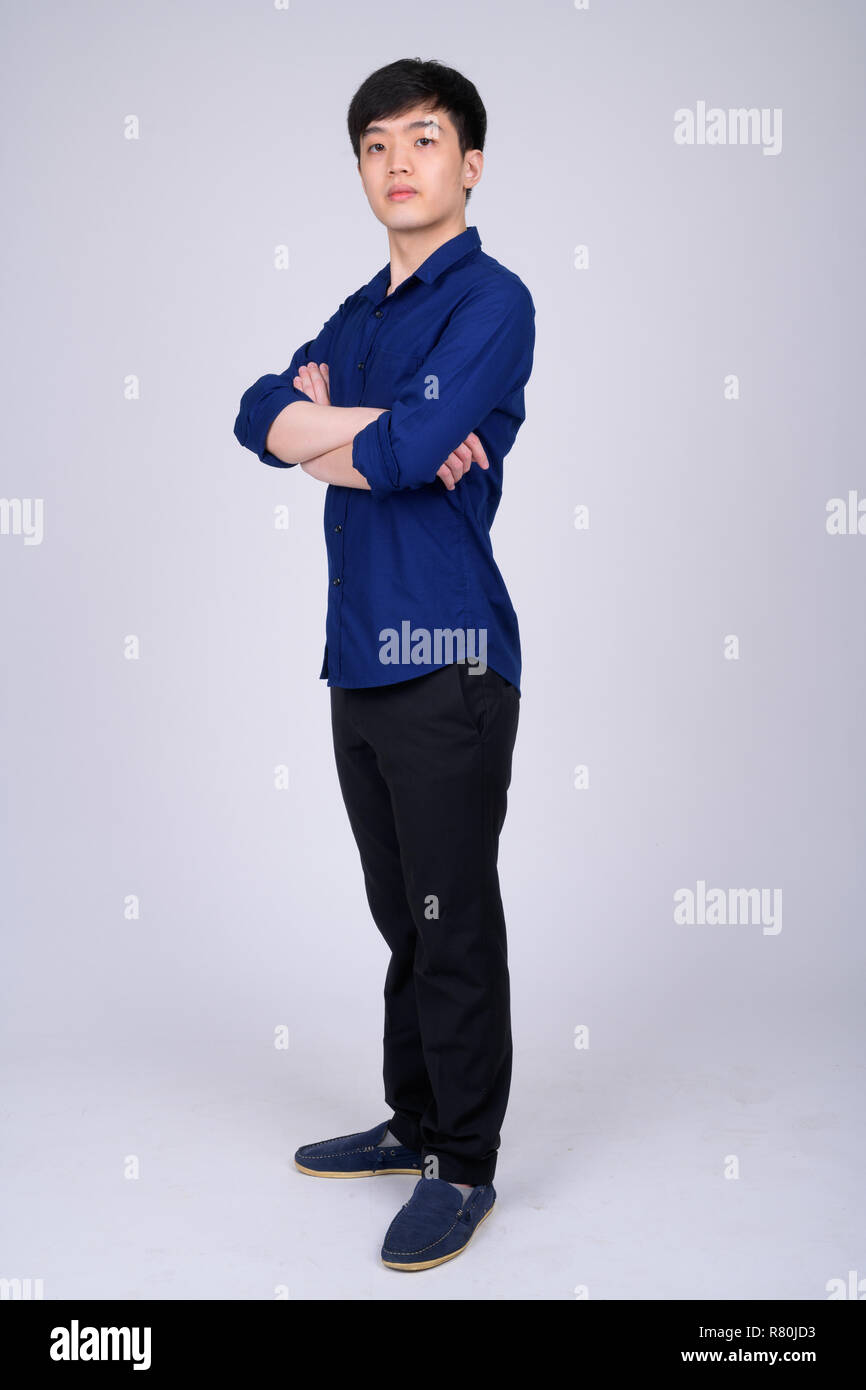 Full body shot of young Asian businessman standing with arms crossed ...