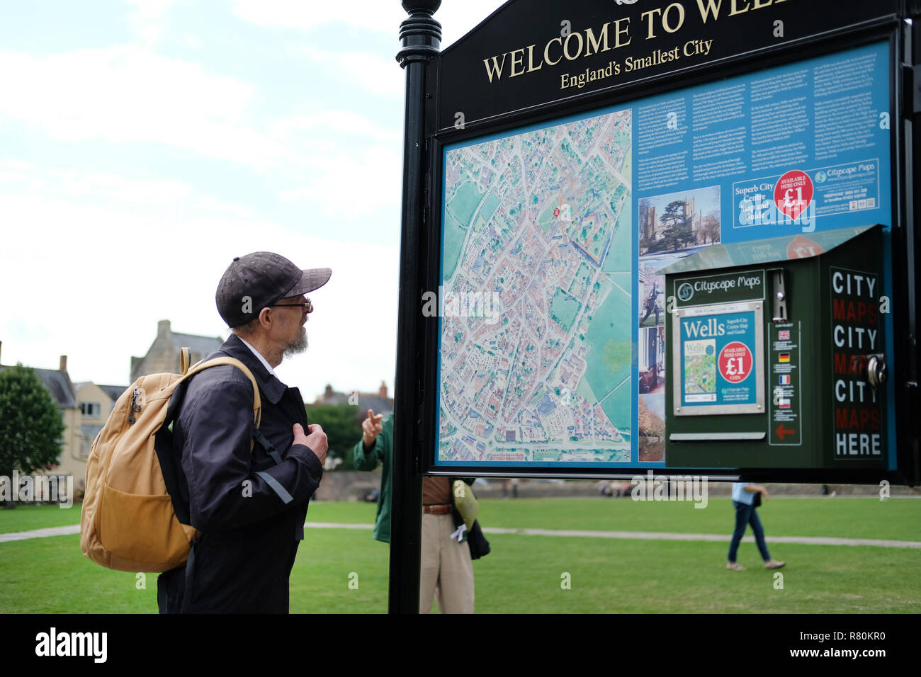 A tourist reading a map on the green outside Wells Cathedral. Stock Photo