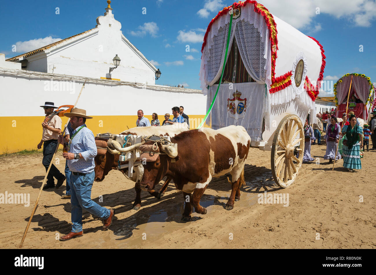 During a famous Pentecost pilgrimage the village of El Rocio converts into a colourful spectacle with beautifully decorated ox-carts, dressed up men and women wearing beautifully coloured gypsy dresses. Huelva province, Andalusia, Spain. Stock Photo