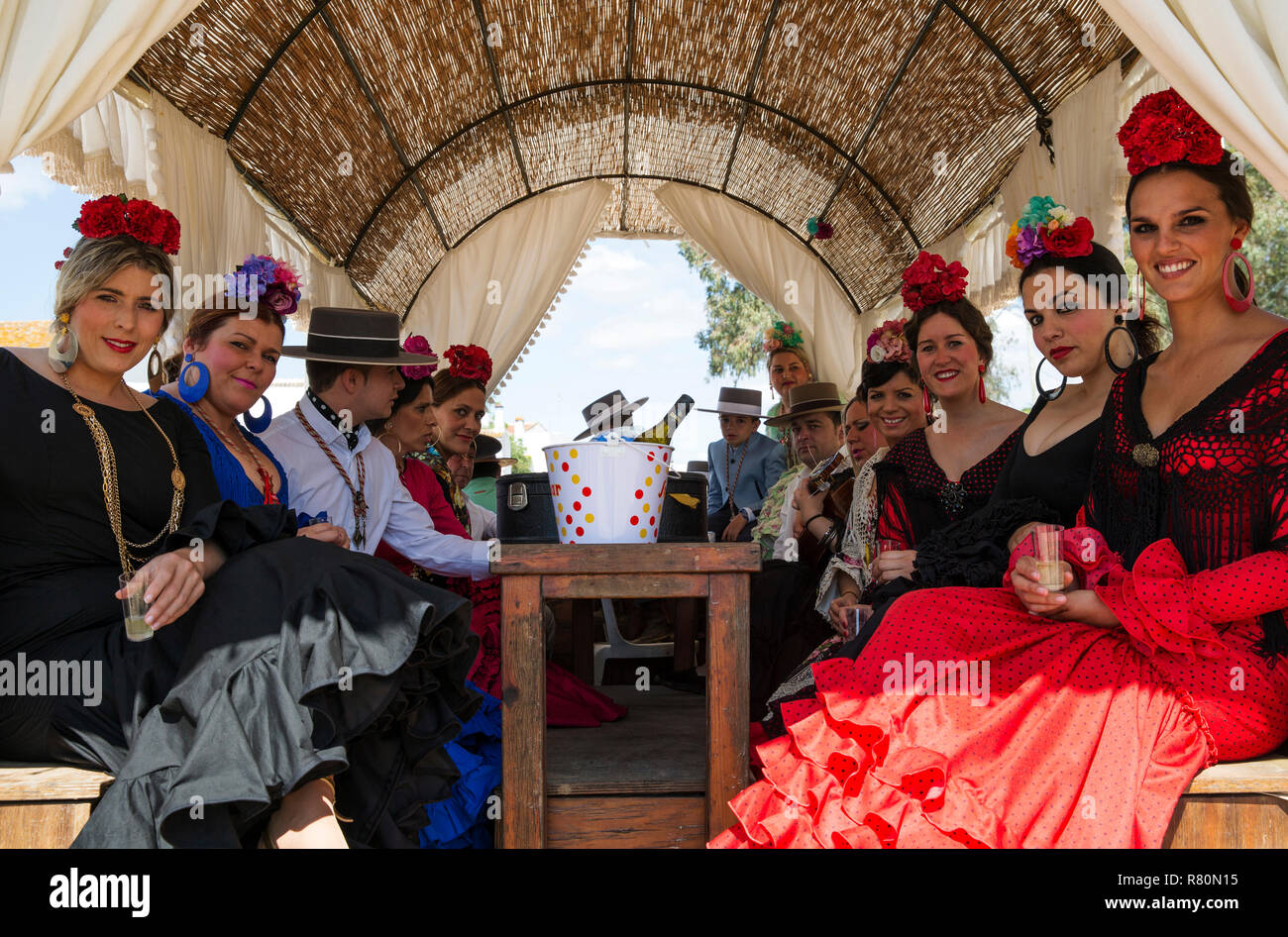 Women wearing beautifully coloured gypsy dresses and dressed up men during the annual Pentecost pilgrimage of El Rocio. Huelva province, Andalusia, Spain. Stock Photo