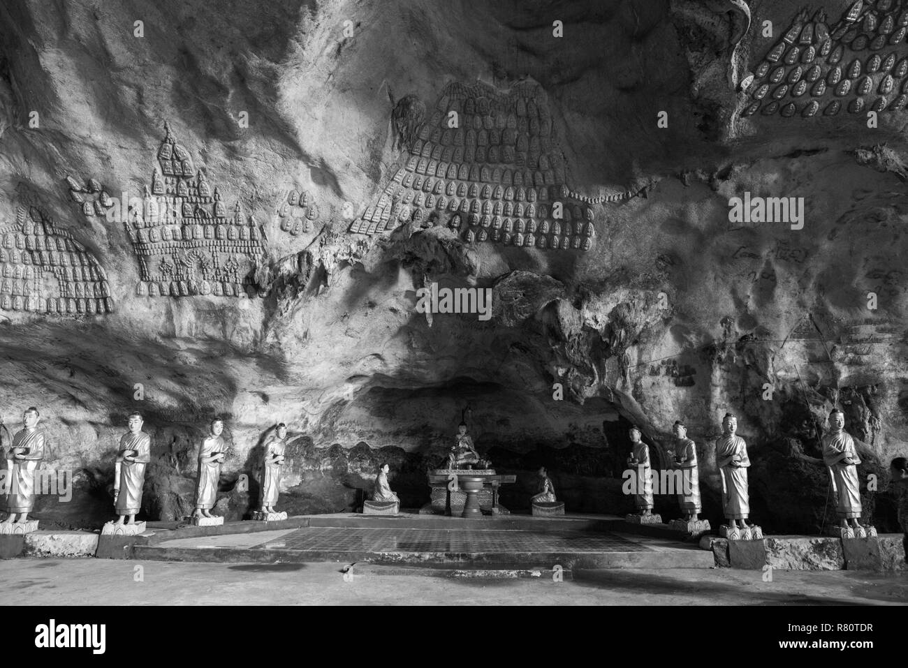 Black and white picture of aligned monks statue and ornated walls inside Sadan Cave, important landmark of Hpa-An, Myanmar Stock Photo