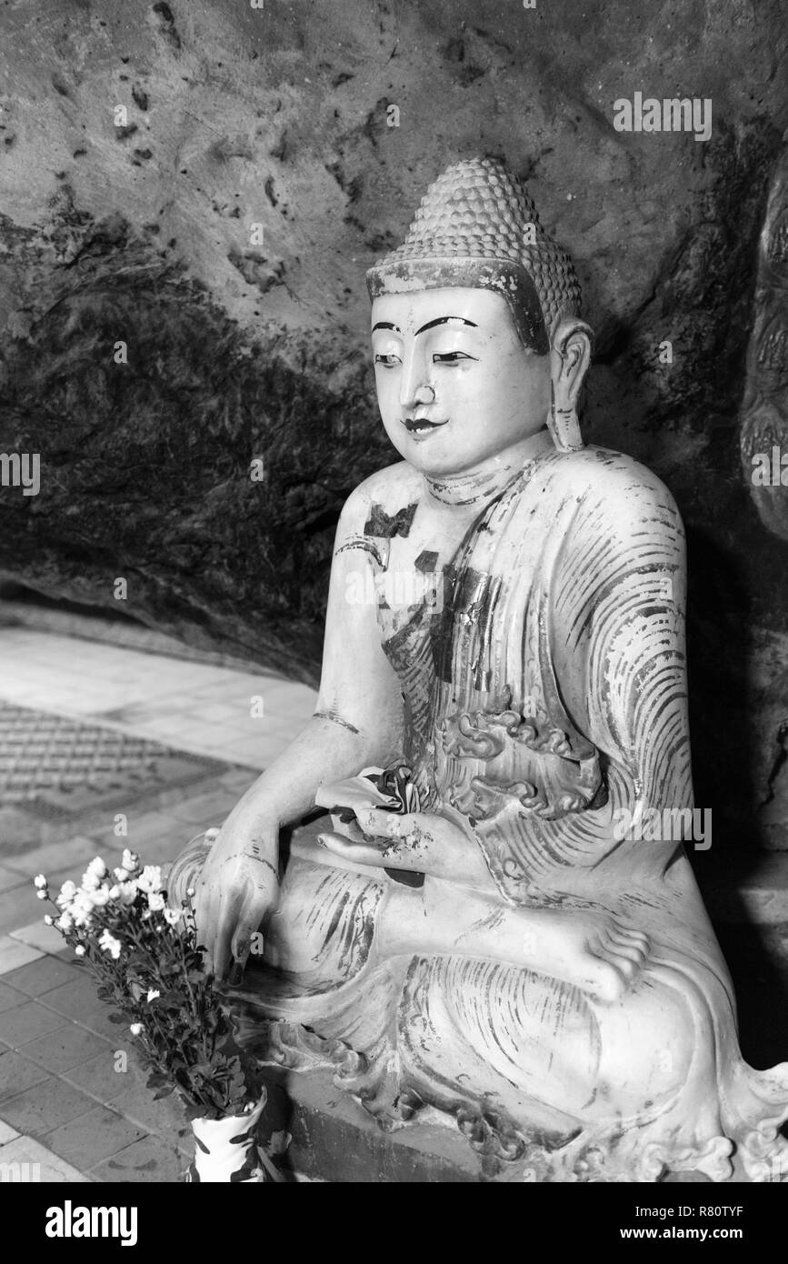 Black and white picture of Buddha statue sitting in meditation position  inside of Kaw Ka Thaung Cave, located close to Hpa-An, Myanmar Stock Photo