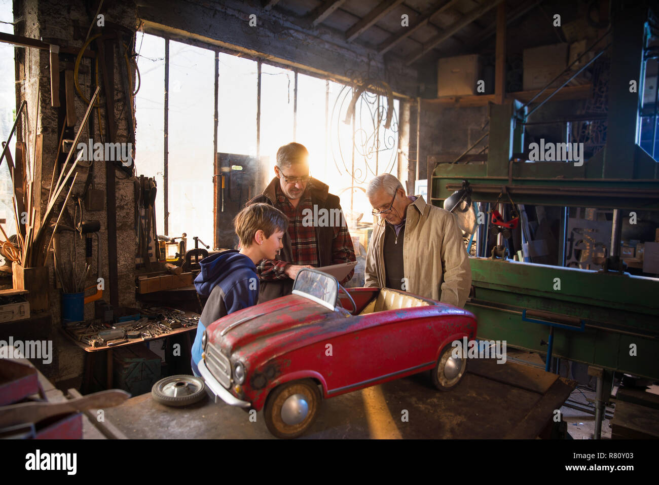 Multi generation family in aDIY workshop to repair a pedal car Stock Photo