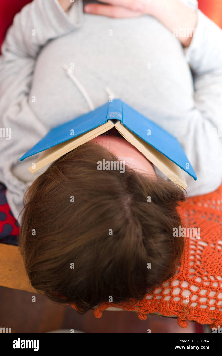close up aerial view of a young man lying asleep on a red sofa with a