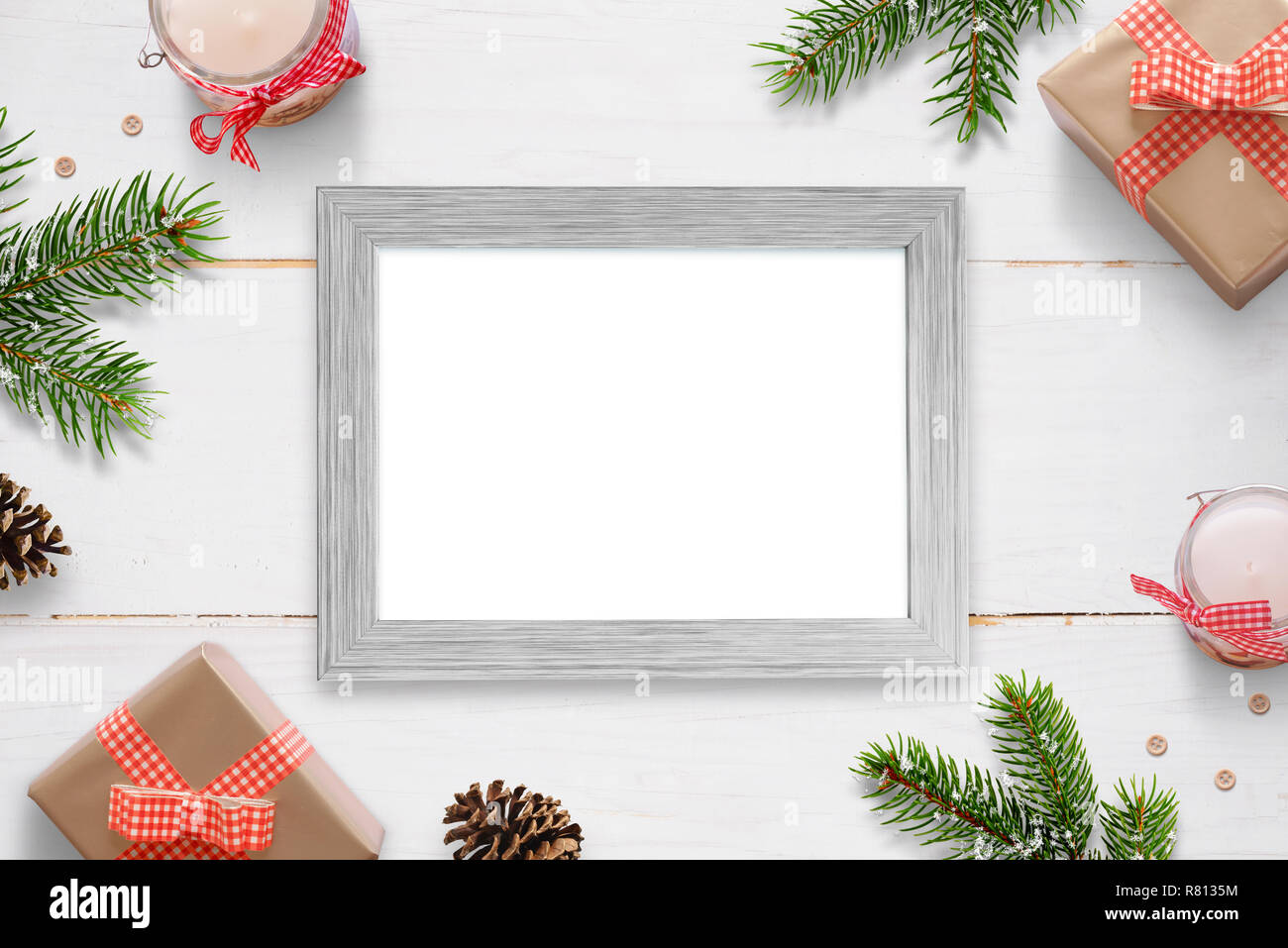 Horizontal photo frame surrounded with Christmas New Year gifts, tree branches and decorations. Isolated frame for photo mockup. Stock Photo
