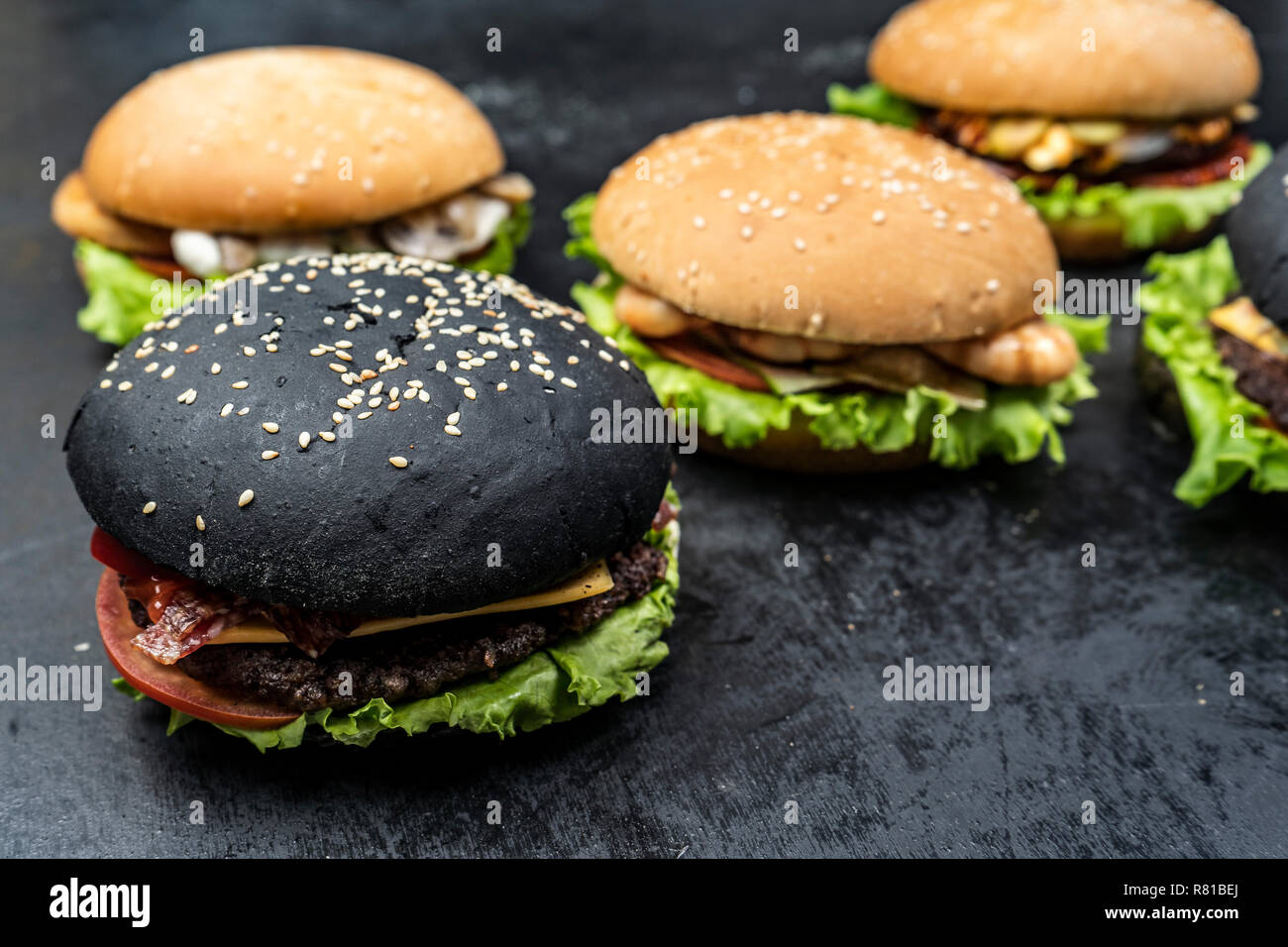 Three hamburger with beef meat burger and fresh vegetables on dark background. Tasty food. Stock Photo