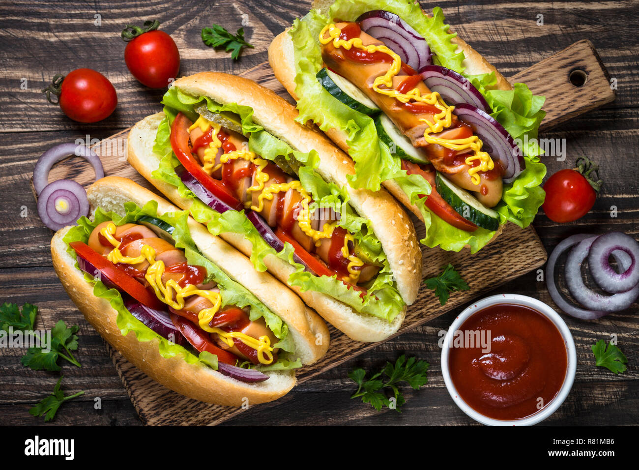 Hot dog with fresh vegetables on wooden table. Stock Photo
