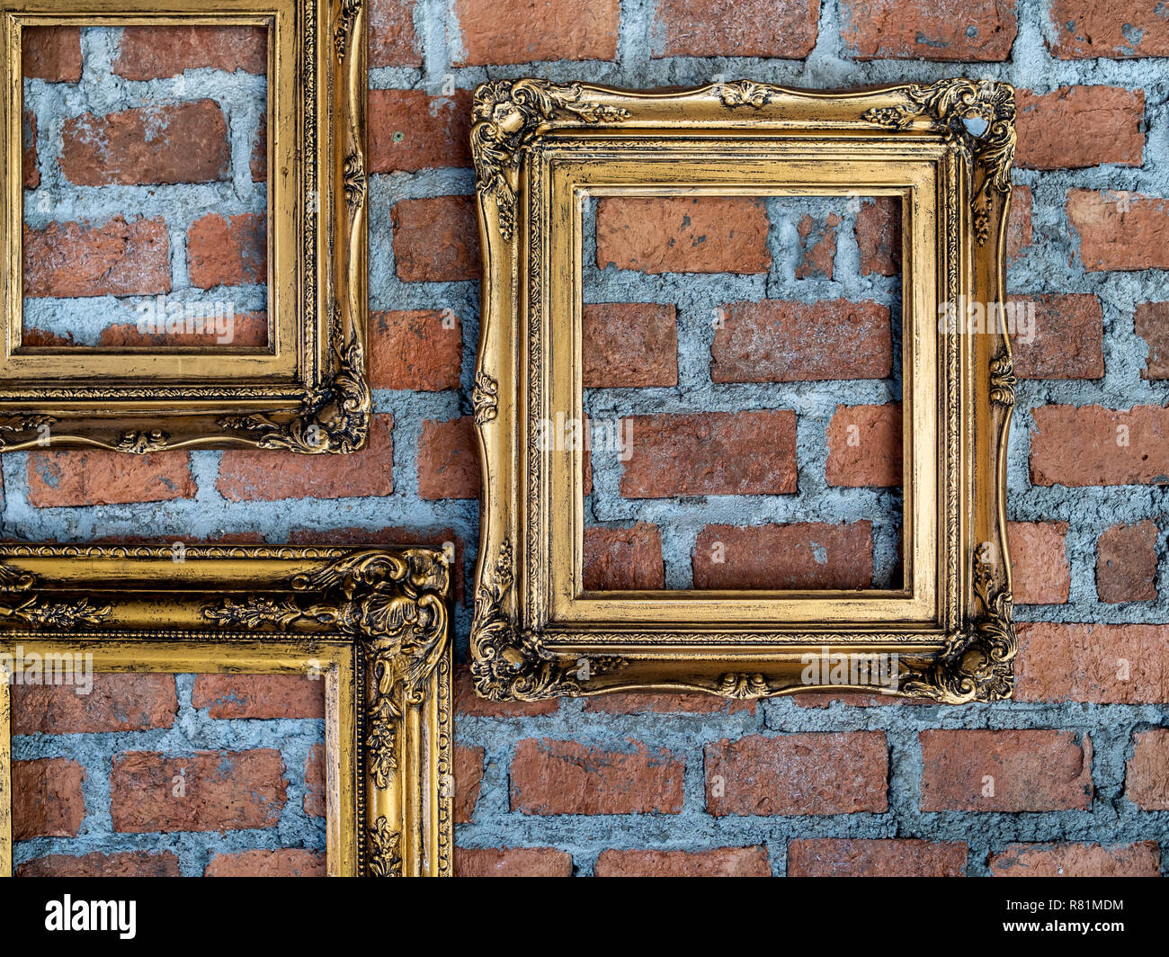 Three empty old ornate golden frames hanging on brick wall. Stock Photo