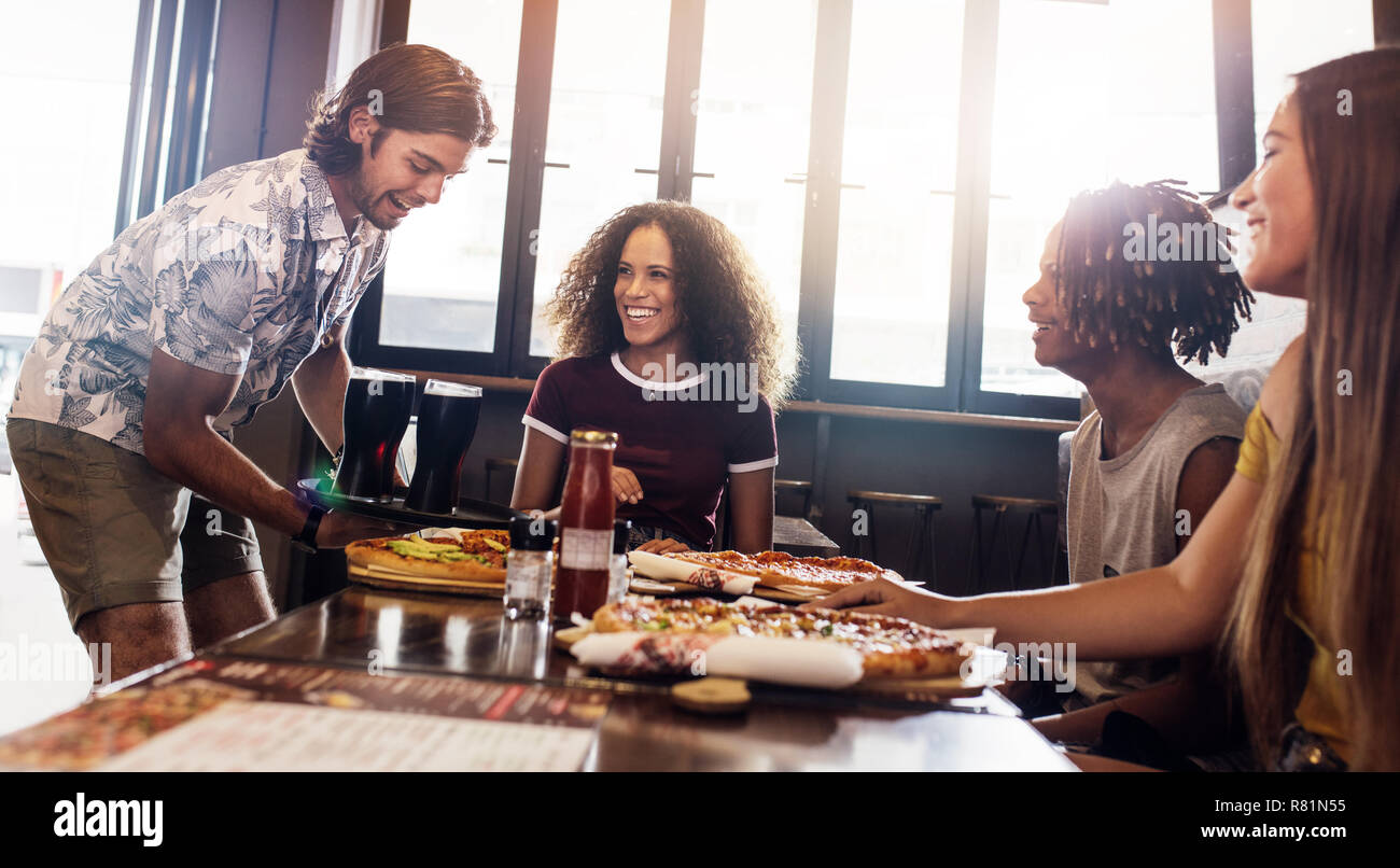 Group of men and women at pizza restaurant. Multi-ethnic friends having lunch together at fast food restaurant. Stock Photo