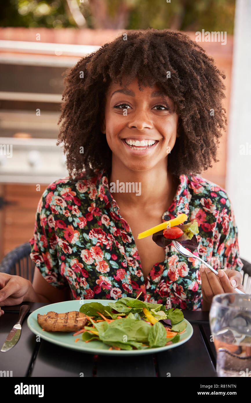 Young black woman eating lunch at a table outside, vertical Stock Photo