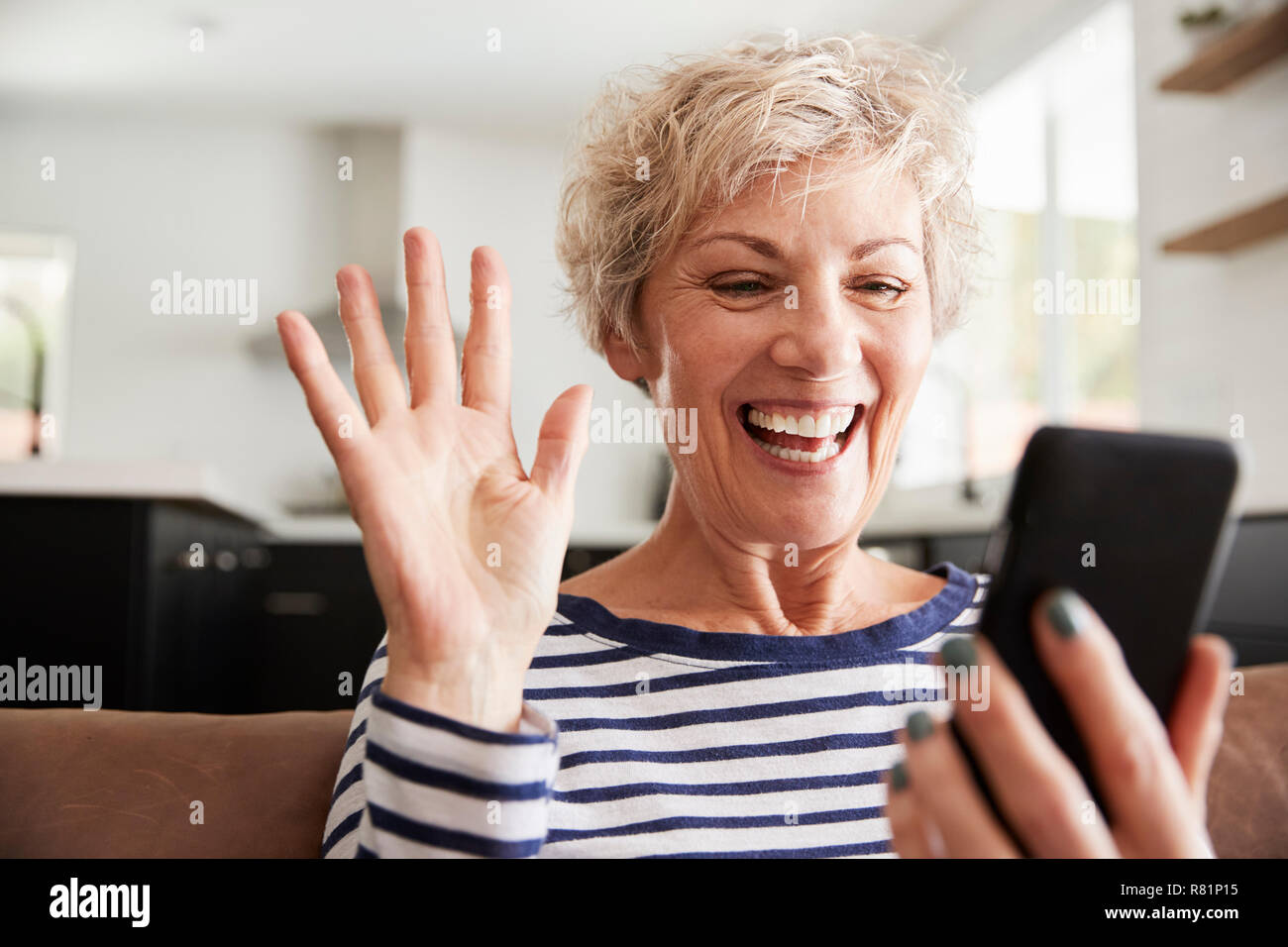Senior woman video calling on smartphone at home, close up Stock Photo