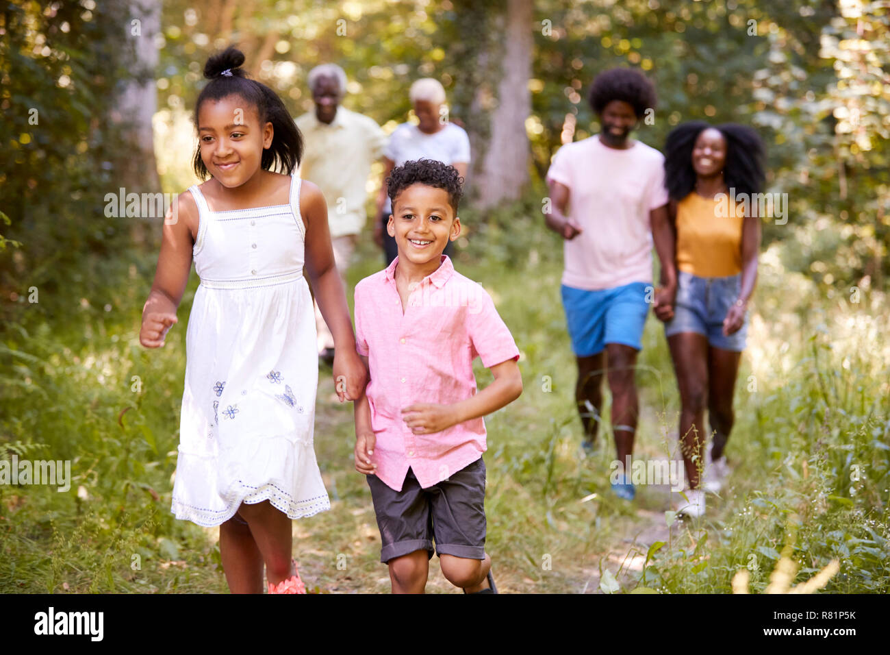 Two kids ahead of their family during a walk in a forest Stock Photo