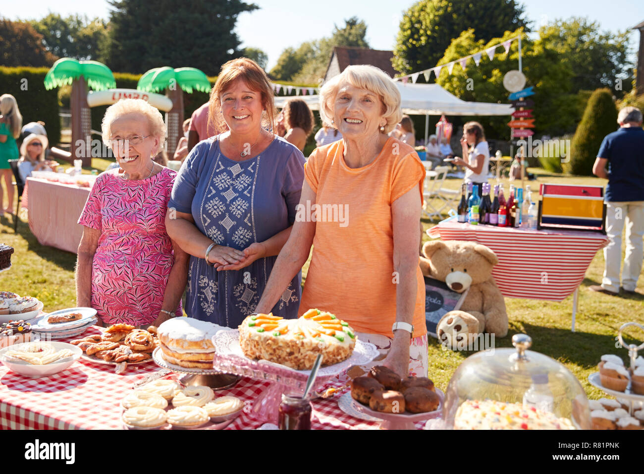 Portrait Of Women Serving On Cake Stall At Busy Summer Garden Fete Stock Photo