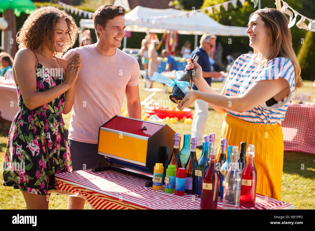 Couple Winning Prize At Tombola Stall At Busy Summer Garden Fete Stock Photo