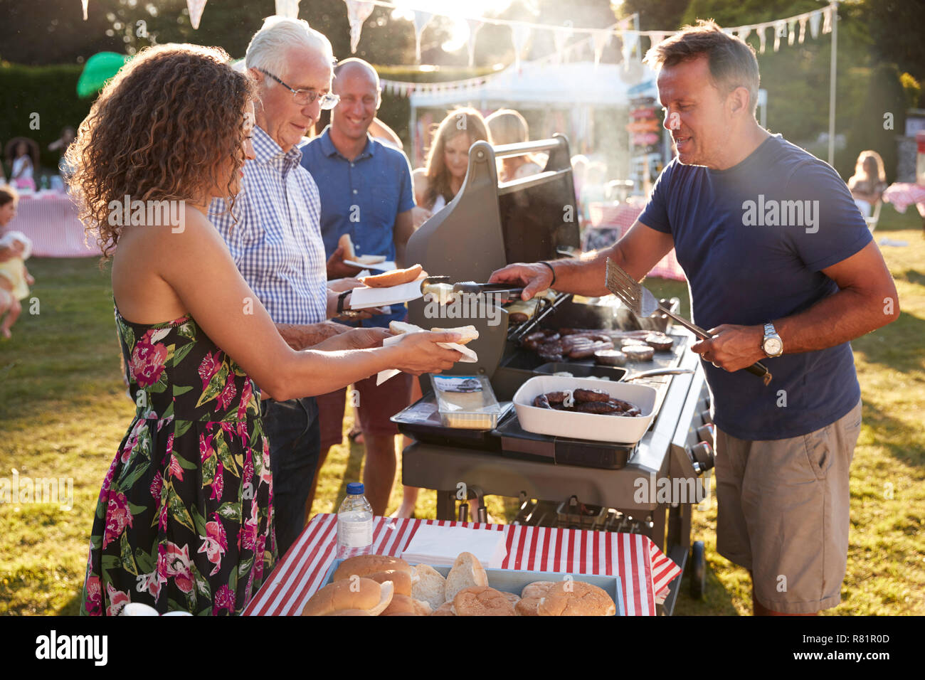 Man Serving On Barbeque Stall At Summer Garden Fete Stock Photo