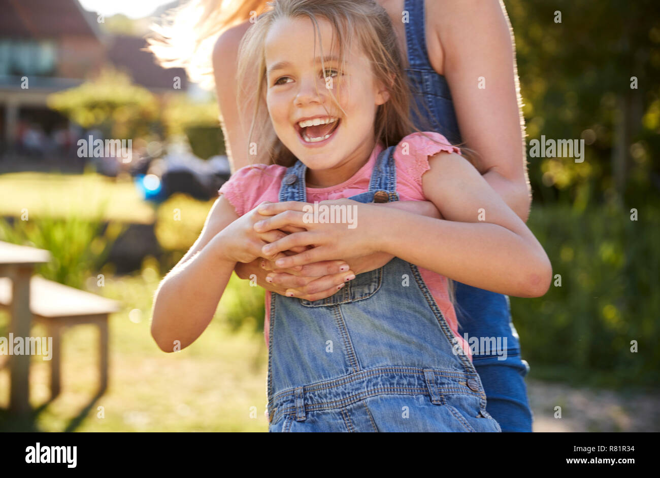 Close Up Of Mother Playing Game And Swinging Daughter Around In Garden Of Summer Pub Stock Photo