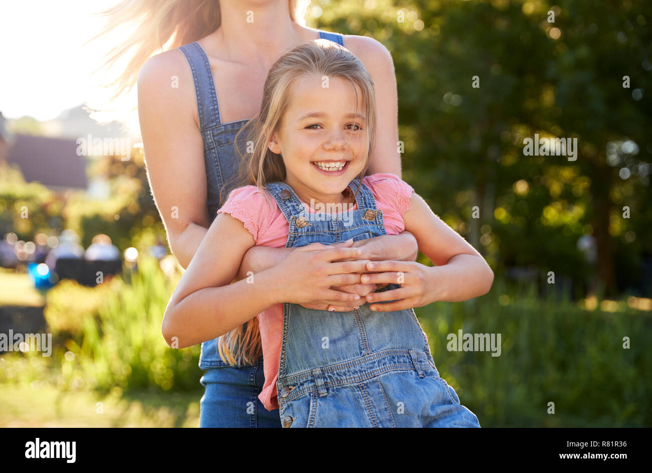 Close Up Of Mother Playing Game And Swinging Daughter Around In Garden Of Summer Pub Stock Photo