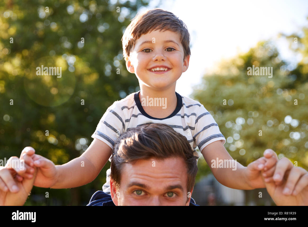 Close Up Of Father Giving Son Ride On Shoulders In Garden Of Pub Stock Photo