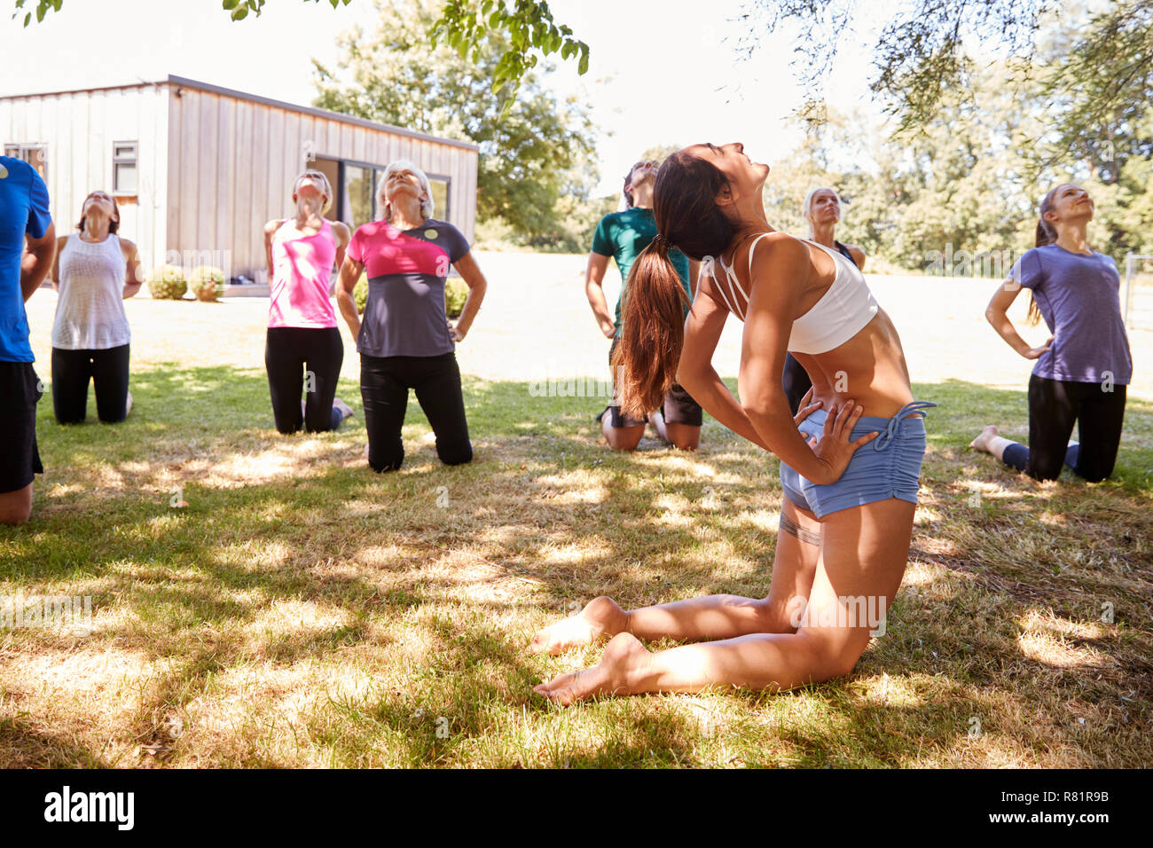 Female Instructor Leading Outdoor Yoga Class Stock Photo
