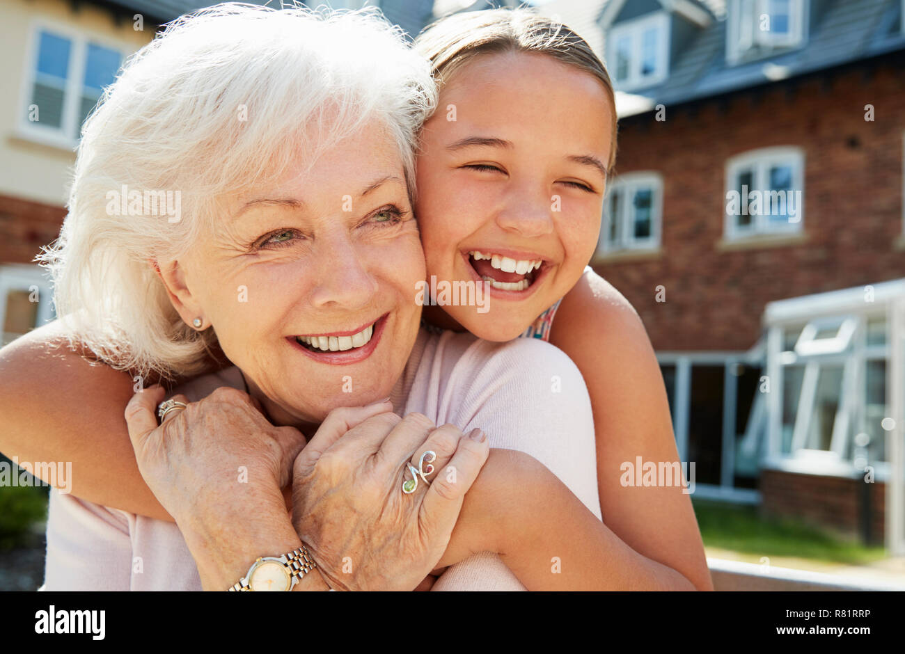 Granddaughter Hugging Grandmother On Bench During Visit To Retirement Home Stock Photo
