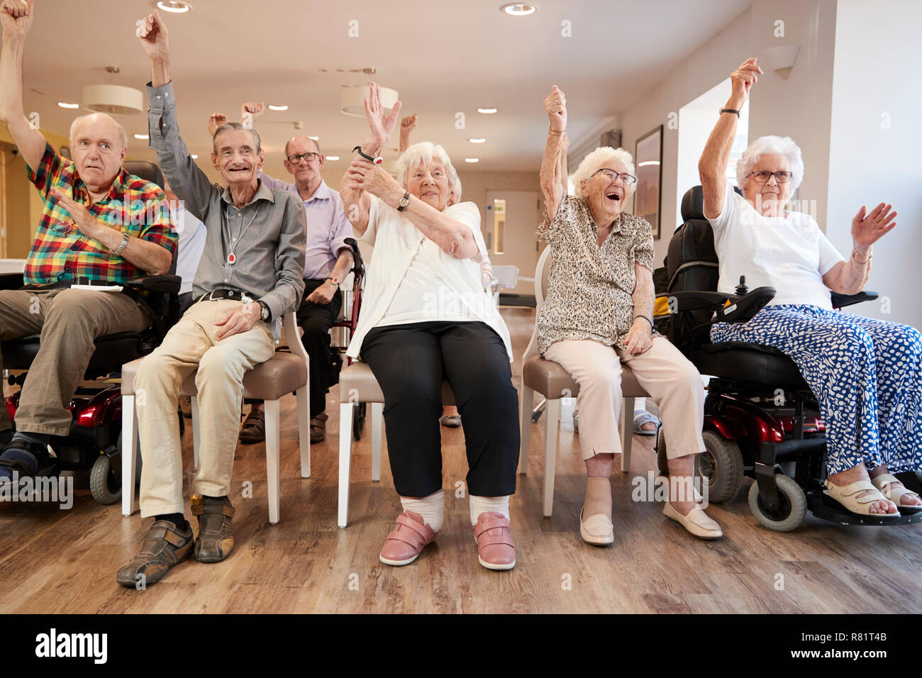 Group Of Seniors Enjoying Fitness Class In Retirement Home Stock Photo