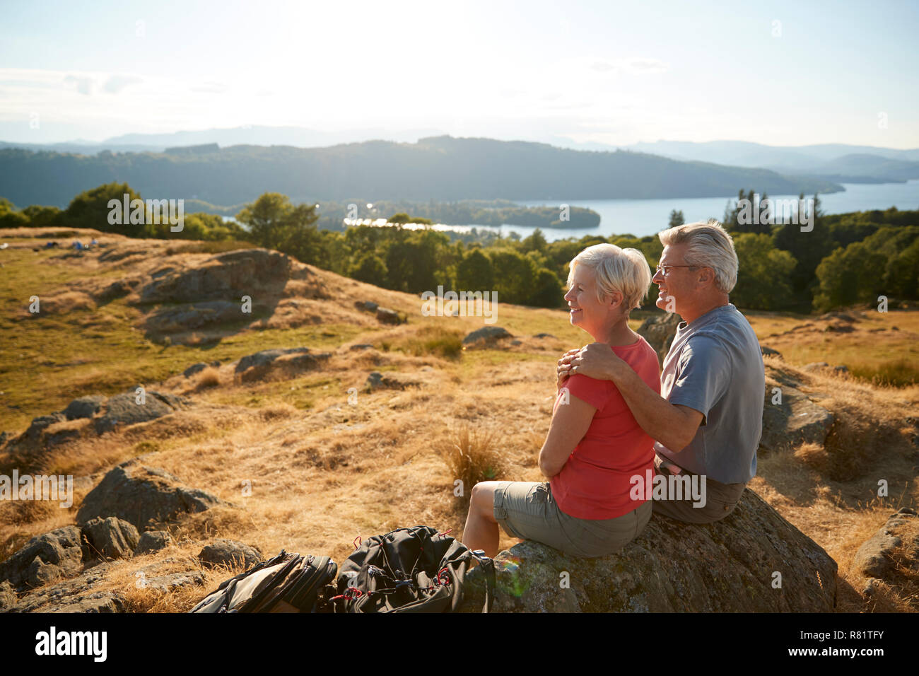 Senior Couple Resting At Top Of Hill On Hike Through Countryside In Lake District UK Stock Photo