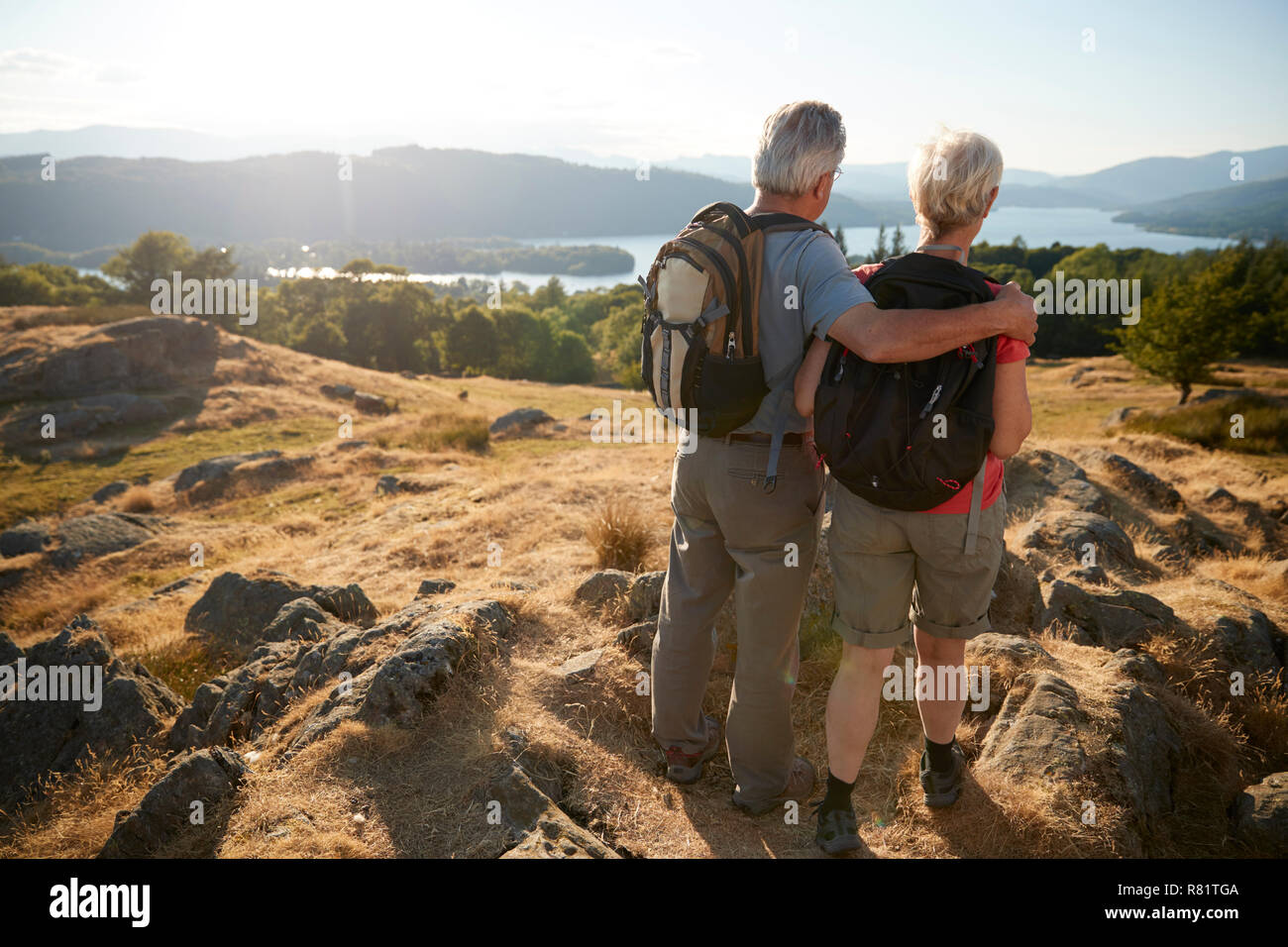 Rear View Of Senior Couple Standing At Top Of Hill On Hike Through Countryside In Lake District UK Stock Photo